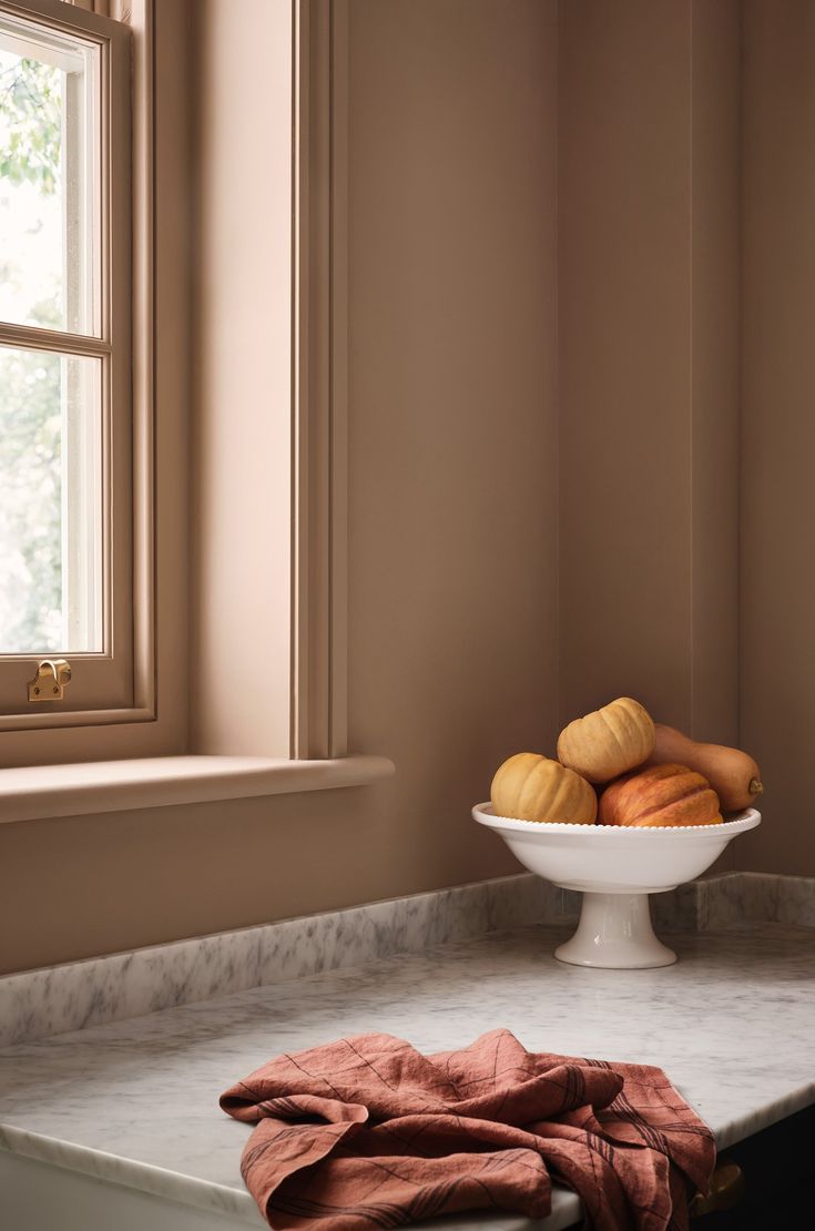 a white bowl filled with croissants sitting on top of a counter next to a window