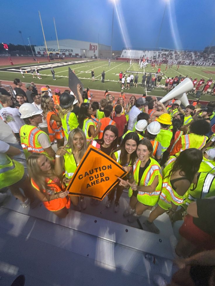 a group of people in safety vests posing for a photo on a football field