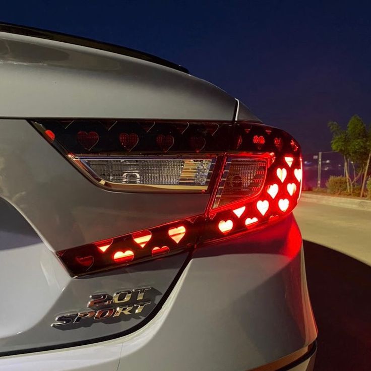 the tail lights of a silver car are shown at night