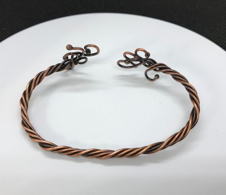 This twisted copper bracelet has been antiqued, polished and sealed to prevent tarnishing. It is 7" long but adjustable to your wrist. The ends have been melted and curled for a one of a kind look. Sealed with Protectaclear. ProtectaClear is a clear, protective coating that is tough enough to protect jewelry and is safe for wear against skin. ProtectaClear is practically invisible once applied and will seal and protect jewelry from tarnish, oxidation, and corrosion Adjustable Wire Wrapped Bronze Cuff Bracelet, Adjustable Hand Forged Bronze Bracelets, Adjustable Bracelet With Antique Finish, Unique Adjustable Bracelets With Antique Finish, Unique Adjustable Bracelet With Antique Finish, Adjustable Bronze Copper Bracelets, Adjustable Bronze Copper Bangle, Adjustable Brown Copper Bangle, Adjustable Hand Wrapped Bronze Cuff Bracelet