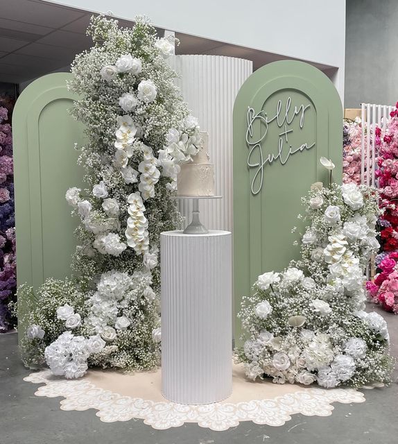 a white vase with flowers on it sitting in front of a sign