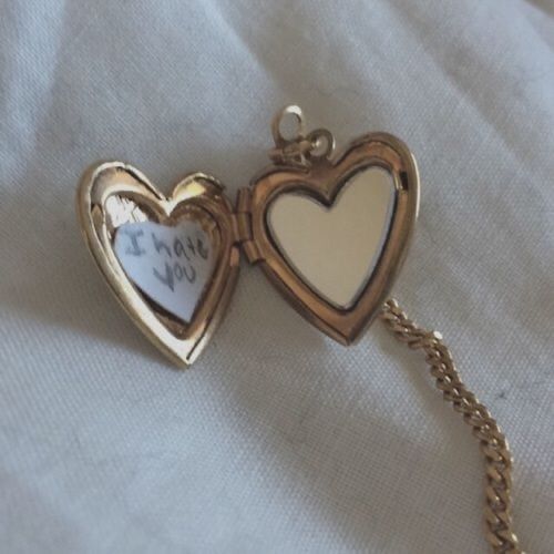 two heart shaped lockes with writing on the inside, attached to a gold chain