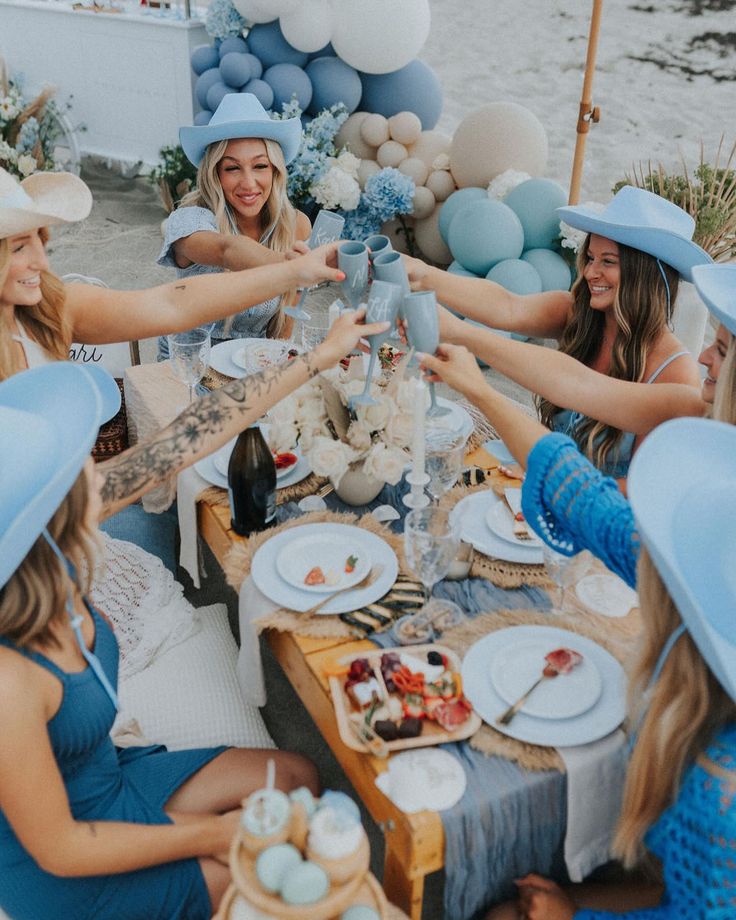 a group of women sitting at a table with hats on their heads and plates in front of them