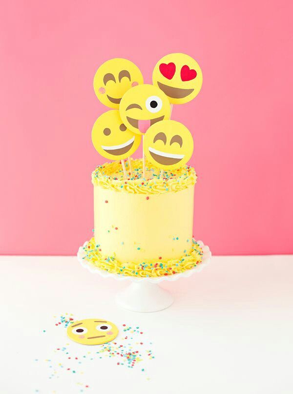 a yellow cake topped with three smiley faces on top of a white frosted cake covered in sprinkles