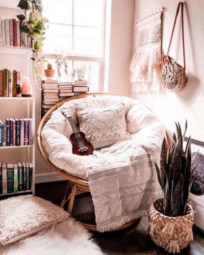 a living room with a chair, bookshelf and potted plants in it