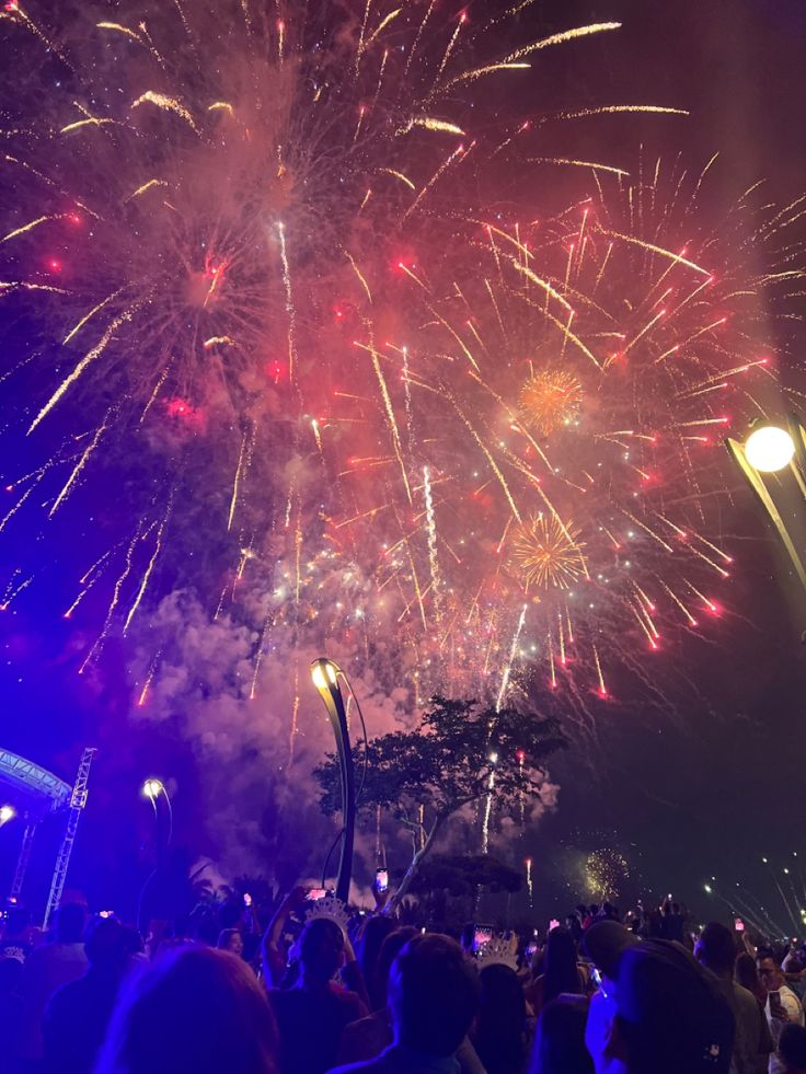 fireworks are lit up in the night sky with people standing around and watching from their seats