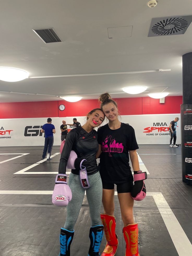 two women standing next to each other in a gym with roller skates on their feet