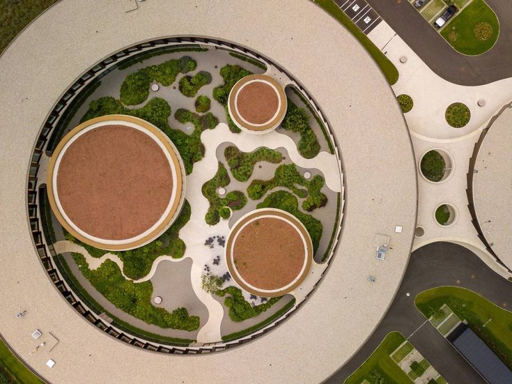 an aerial view of a circular building with trees in the center