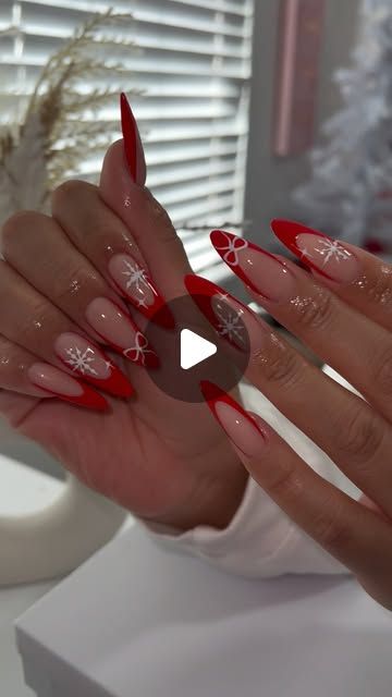 a woman's hands with red and white nail polish on them, in front of a window