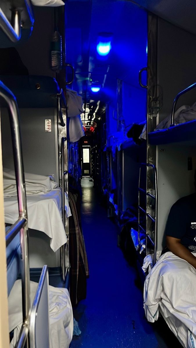 a man sitting in the middle of a room filled with bunk beds and white sheets