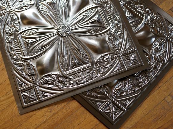 two decorative metal plates sitting on top of a wooden table next to eachother