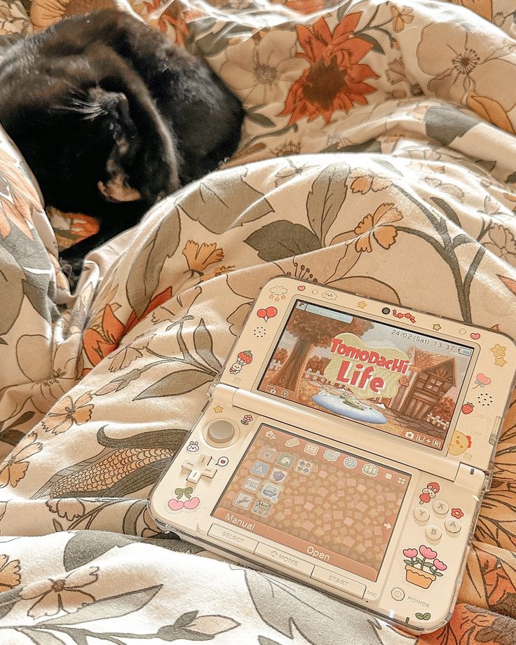 a black cat laying on top of a bed next to an electronic device