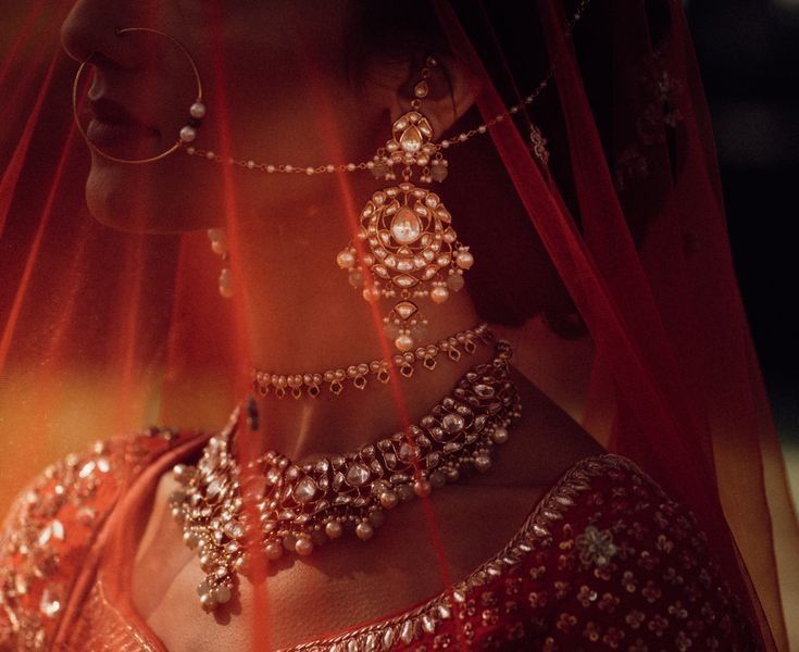 a woman in a red sari with jewelry on her neck