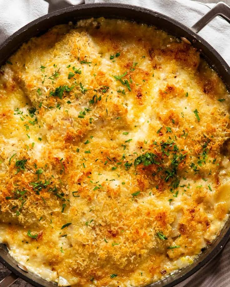 a casserole with cheese and herbs in a pan on a white table cloth