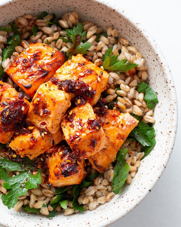 a white bowl filled with rice and tofu on top of spinach leafy greens