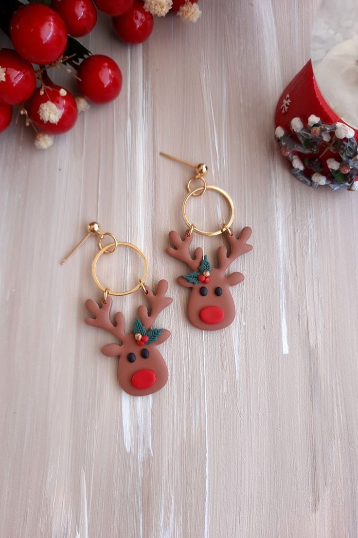 pair of deer earrings on white table next to red berries