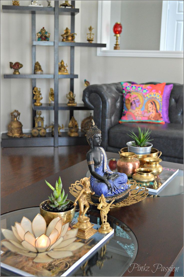 a living room filled with furniture and a buddha statue on top of a coffee table