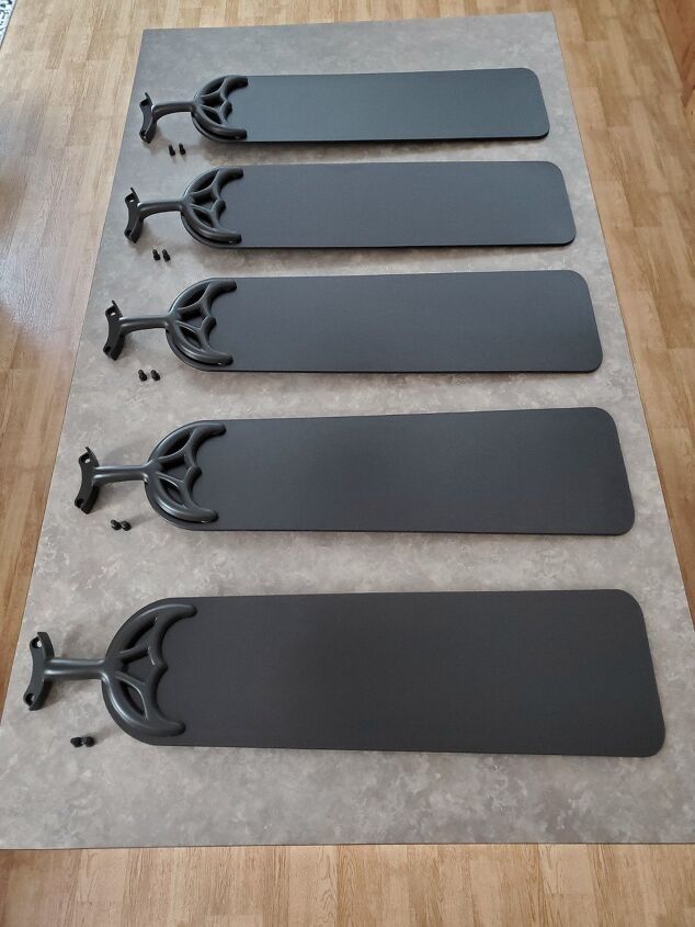 four black door handles on top of a wooden floor next to a white and gray wall