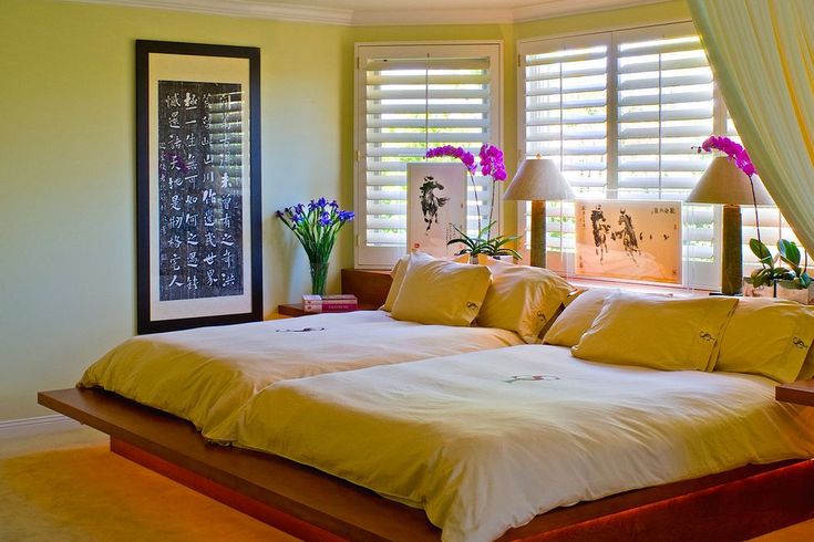 a bed sitting in the middle of a bedroom next to two windows