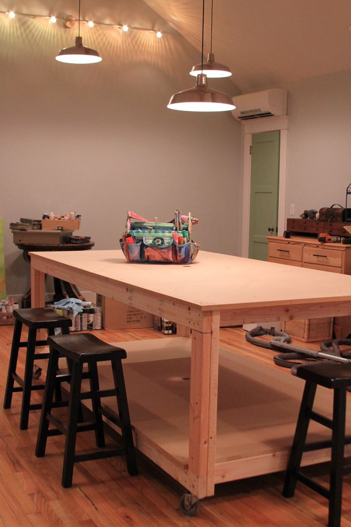 a kitchen island with stools in front of it and lights hanging from the ceiling