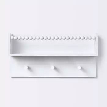 a white shelf with three hooks on it