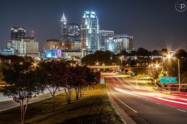 the city skyline is lit up at night with lights streaking down it's sides