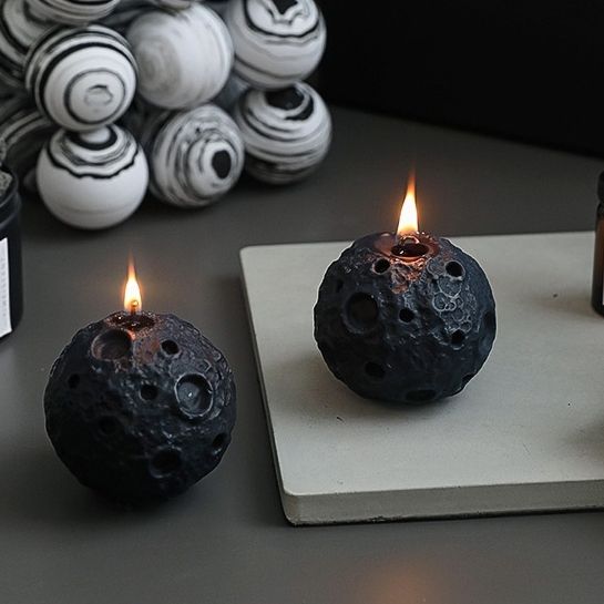 two black candles sitting on top of a white plate