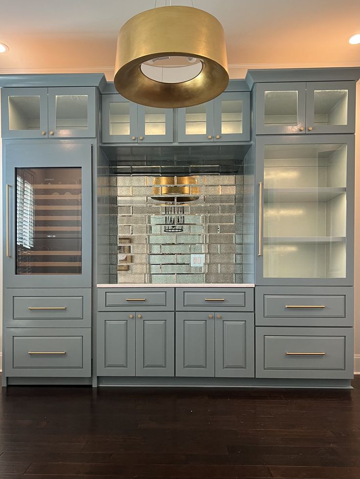 a kitchen with gray cabinets and gold lights