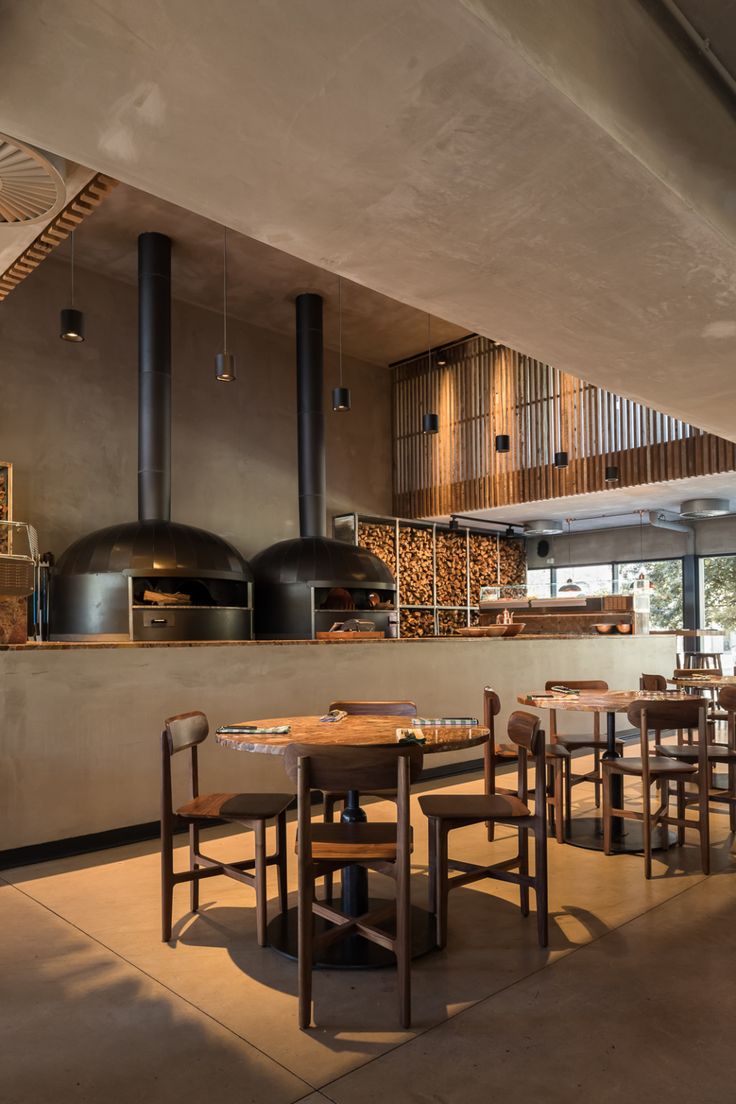 a restaurant with wooden tables and chairs in front of an open fire place on the wall