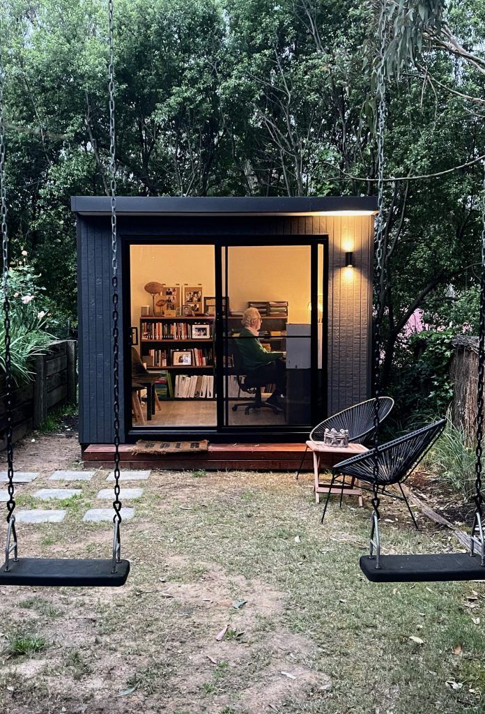 a couple of swings sitting in front of a small building with glass doors and windows