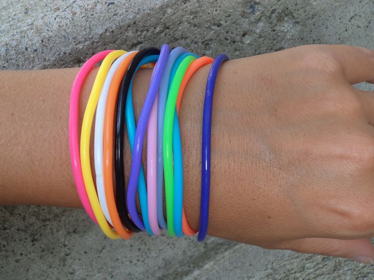 a woman's arm with several different colored bracelets on it