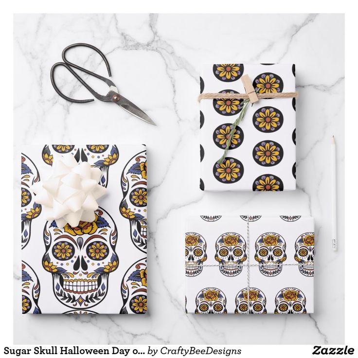 wrapping paper and scissors on a marble table with skull designs, white roses and black dots