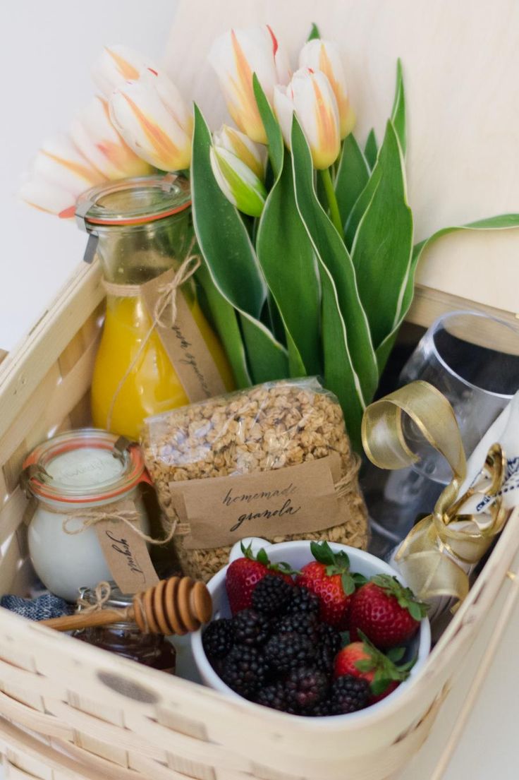 a wicker basket filled with assorted food and drink items next to tulips