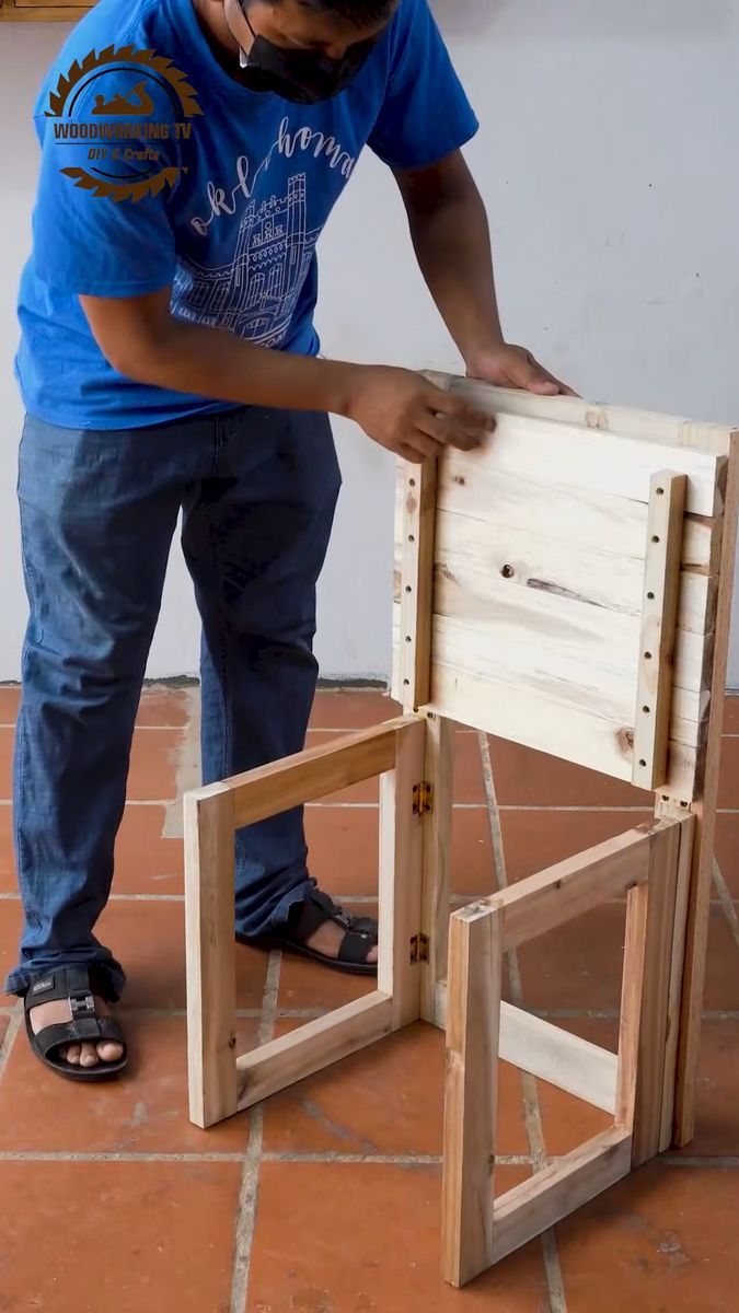 a man working on a chair made out of wooden planks and plywood boards