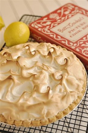 a pie sitting on top of a cooling rack next to lemons and a book