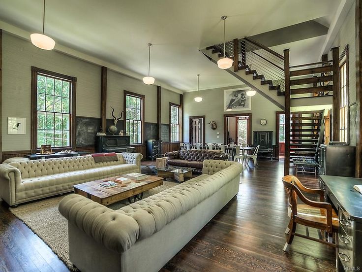 a living room filled with lots of furniture and wooden flooring next to tall windows