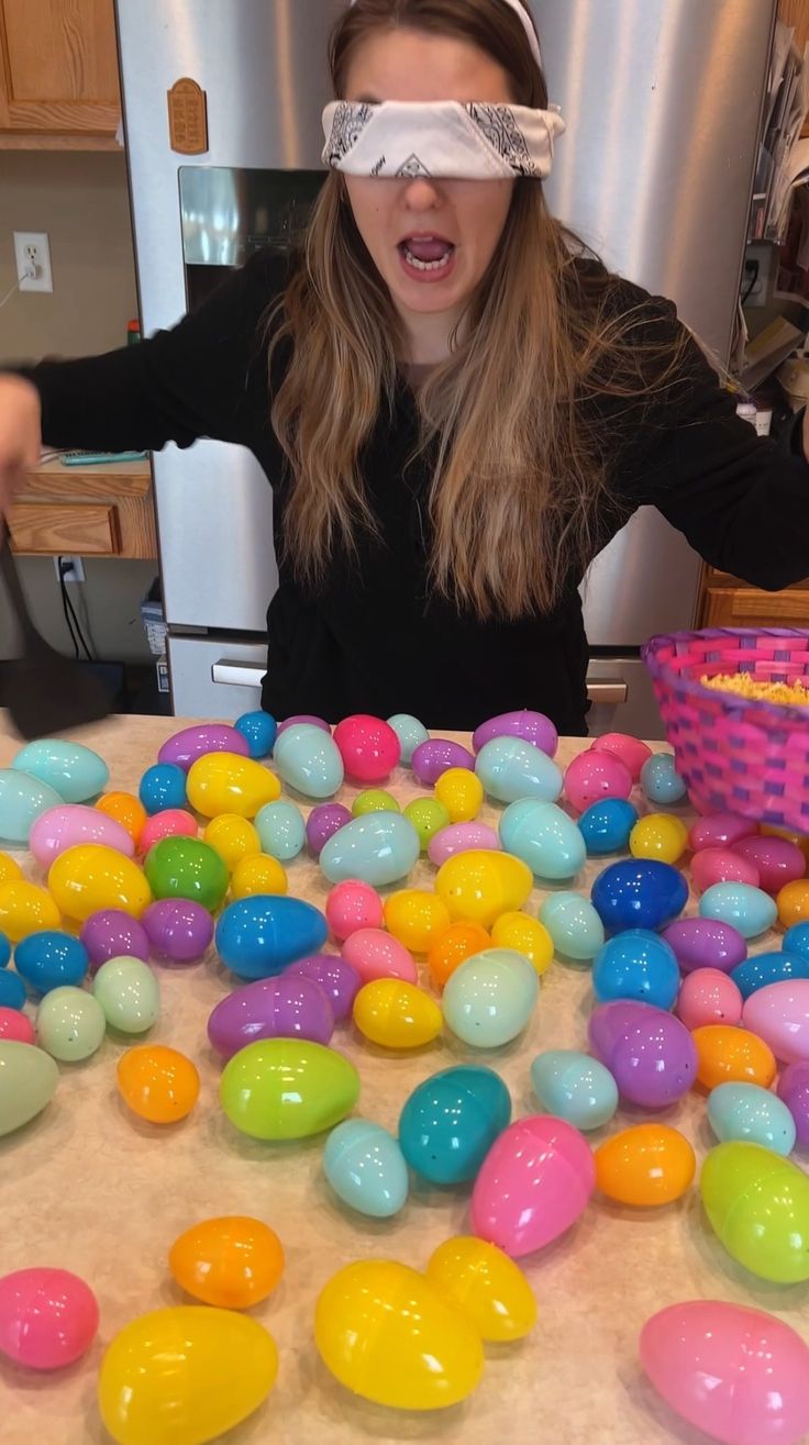 a woman wearing blindfolded glasses standing in front of a table filled with easter eggs