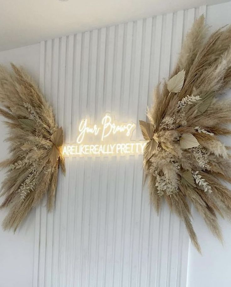 two feathers are hanging on the wall next to a neon sign that reads, you're