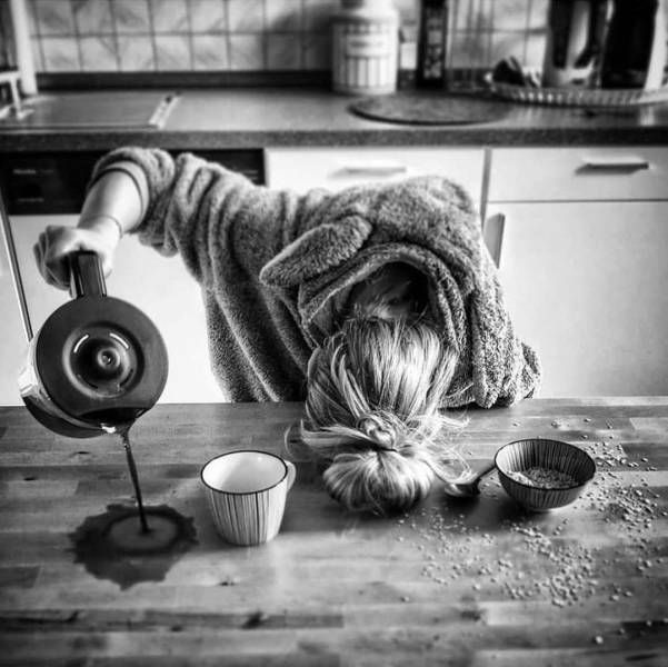 a woman bending over with her head on top of a table next to cups and a blender