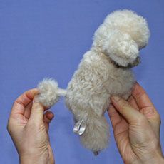 two hands holding a small white stuffed dog