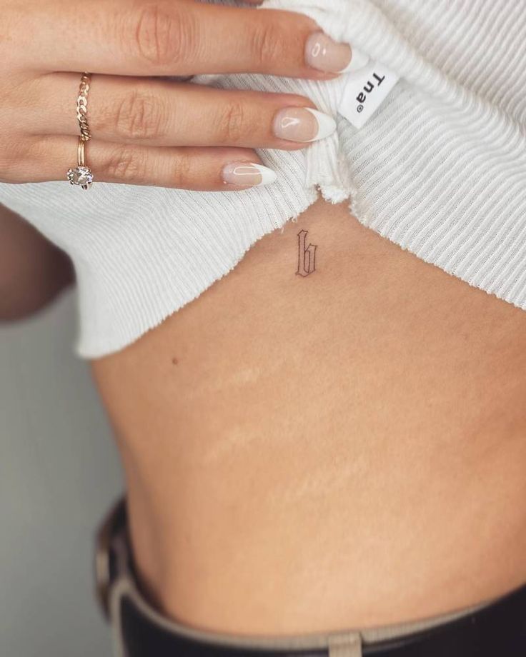 a woman's stomach with a small tattoo on her lower back that reads pi