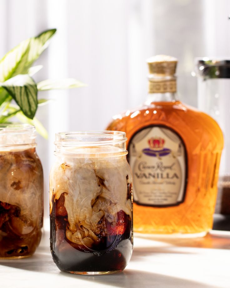 two mason jars filled with food sitting on top of a table next to a potted plant