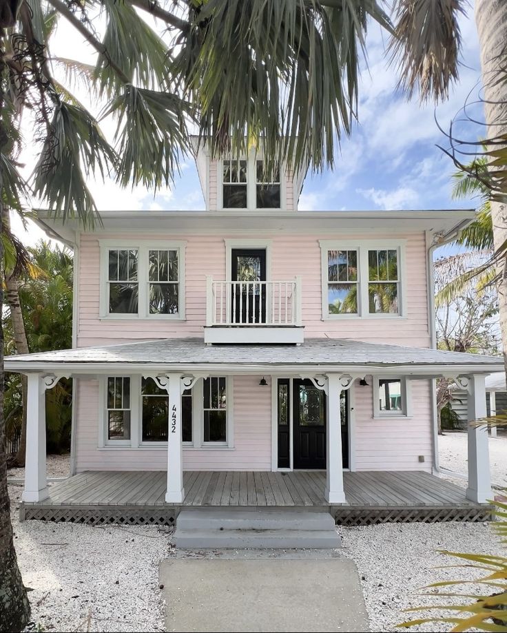 a pink house with white trim and palm trees