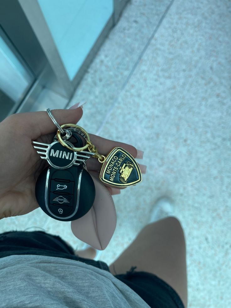 a person holding a car key with a mini badge attached to it's thumb