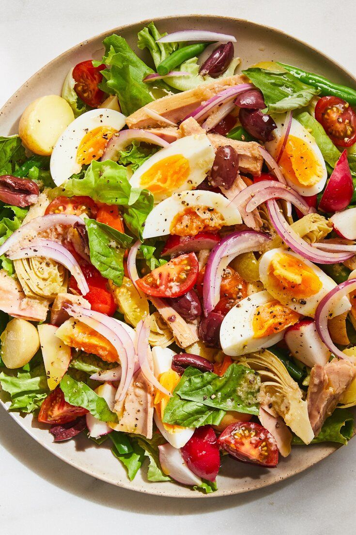 a salad with hard boiled eggs, tomatoes, onions and lettuce on a plate