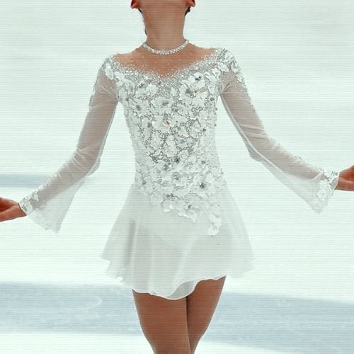 a female figure skating in a short white dress