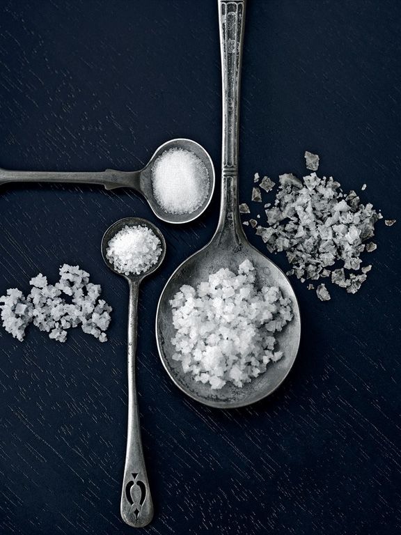 two spoons filled with white sugar next to each other on top of a table