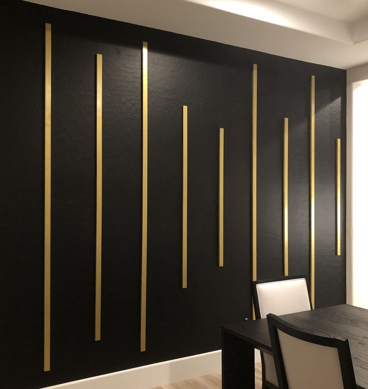 a dining room with black walls and gold lines on the wall