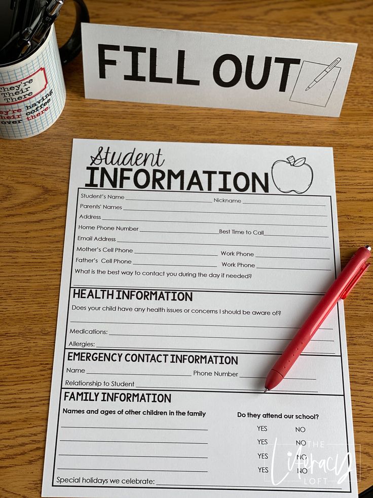 a fill out sitting on top of a wooden table next to a cup and pen