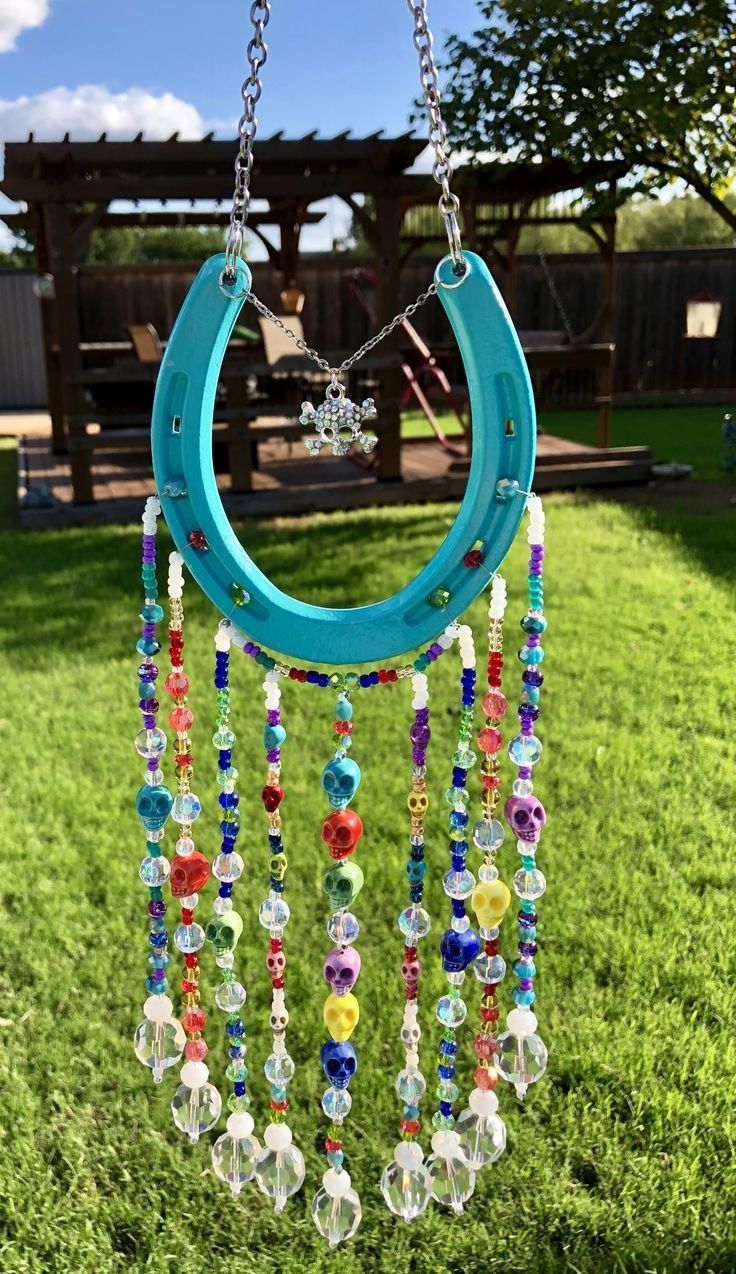 a blue circular wind chime hanging from a chain on top of a grass field